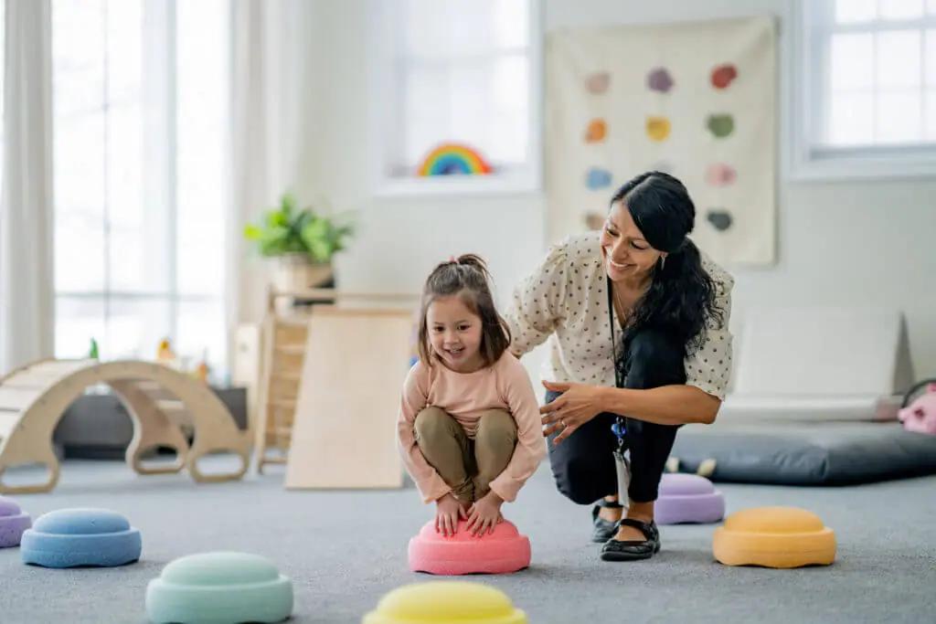 A pediatric therapist supporting a child during a playful physical therapy session