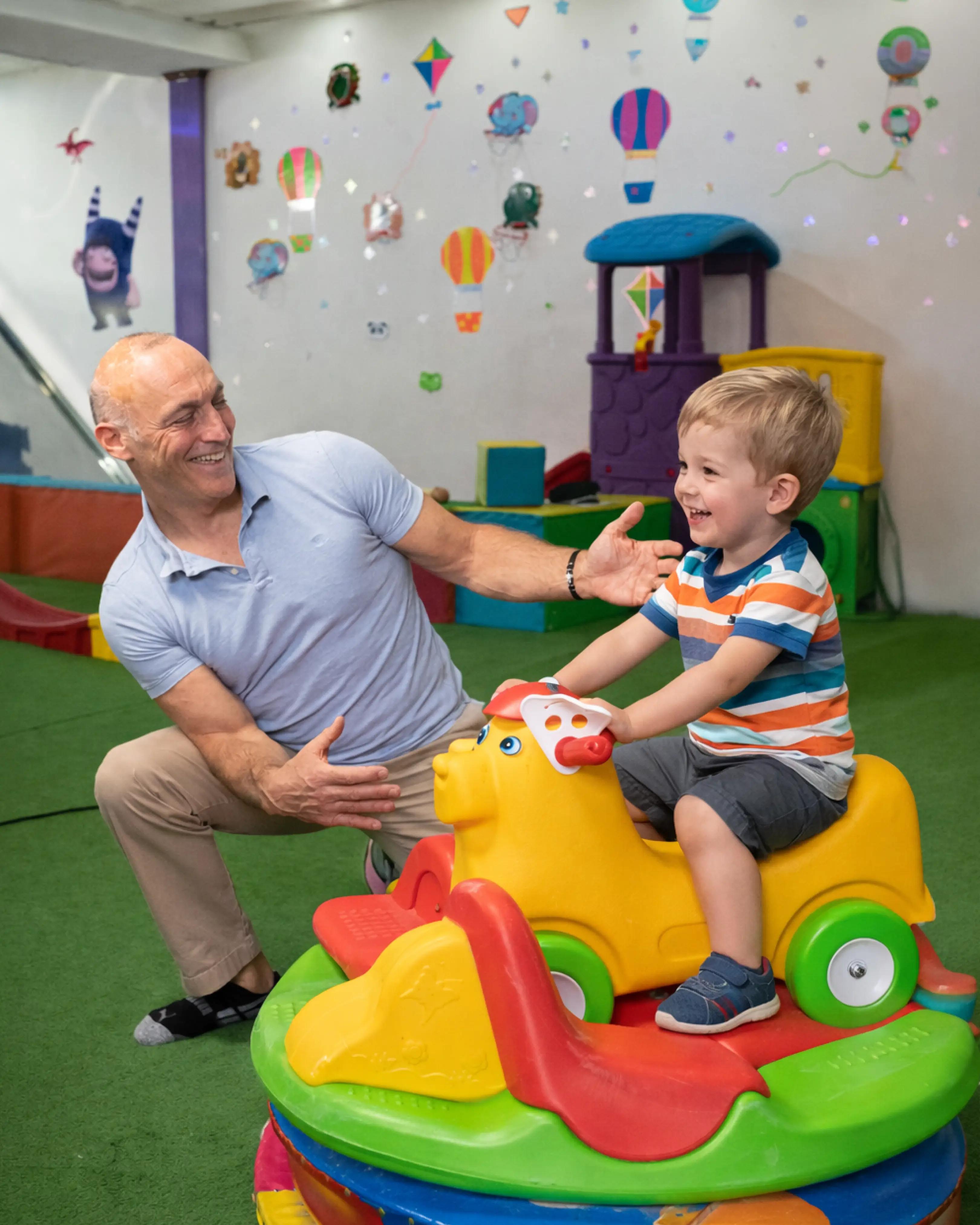 A smiling therapist interacting with a child while a parent stays close in a warm therapy setting